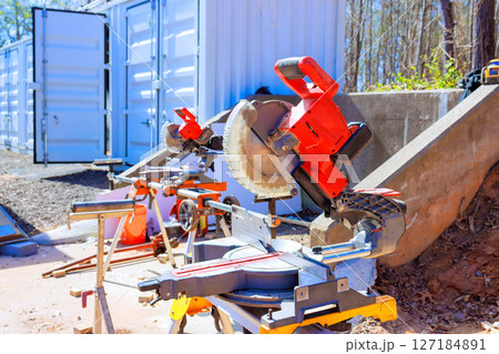 Various power tools are arranged in construction area next to storage units, highlighting an active work environment. Various power tools are arranged in construction area next to storage units, highlighting an active work environment. 127184891