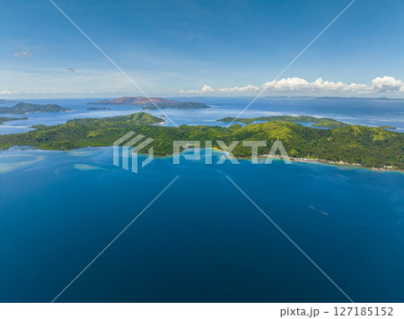 Stunning view of tropical island with small village in coastline.. Blue sea surface and blue skies and clouds. Seascape. Mindanao, Philippines. 127185152