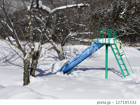 雪に埋もれた青と緑色が綺麗な滑り台 127185332