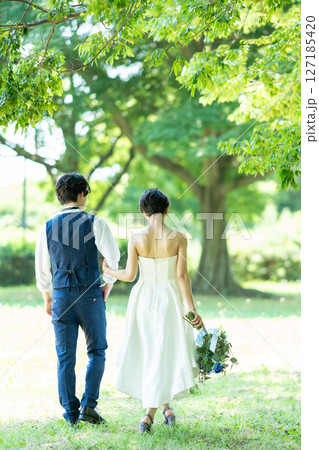腕を組んで歩く新郎新婦の後ろ姿 127185420
