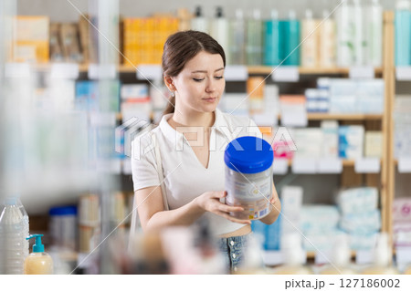 Young woman chooses baby formula at pharmacy Young woman chooses baby formula at pharmacy 127186002