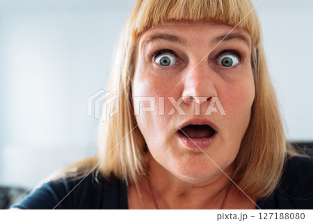 Portrait middle-aged woman, blonde, grimacing in front mirror 127188080