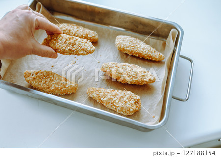 Raw frozen breaded chicken pieces on a baking sheet. Raw frozen breaded chicken pieces on a baking sheet. 127188154