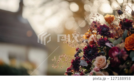 Elegant autumn floral arrangement in warm, muted tones against a bokeh background of golden light. 127188958