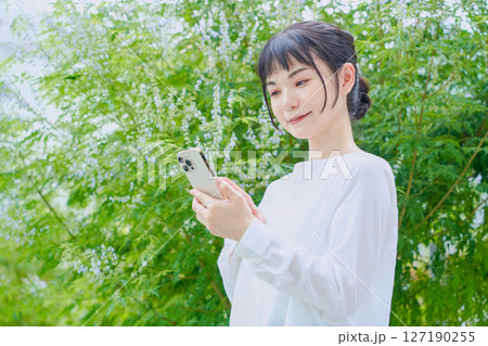 スマートフォンを操作する屋外での爽やかな30代女性 スマートフォンを操作する屋外での爽やかな30代女性 127190255