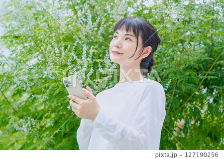 スマートフォンを操作する屋外での爽やかな30代女性 スマートフォンを操作する屋外での爽やかな30代女性 127190256