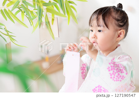 七夕　笹の葉に短冊を飾り付ける2歳の女の子　願い事　笹飾り　願いごと　一夜飾り 127190547