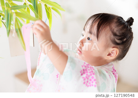 七夕　笹の葉に短冊を飾り付ける2歳の女の子　願い事　笹飾り　願いごと　一夜飾り 127190548