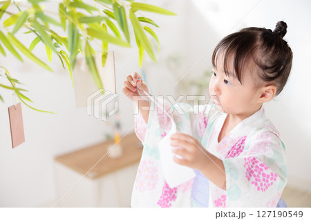 七夕　笹の葉に短冊を飾り付ける2歳の女の子　願い事　笹飾り　願いごと　一夜飾り 127190549