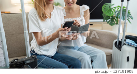 Happy young woman with credit card booking vacation at travel agency or making hotel reservation online 127191909