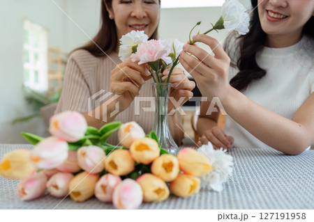 Mother and daughter arrange flower together at home on the weekend, family activities, mother and daughter do activities together on Mother's Day 127191958