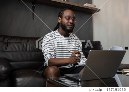 African American business man working with document and laptop at home on couch. work from home concept 127191986