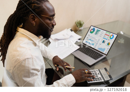 Businesswoman using a calculator to calculate numbers on a company's financial documents, she is analyzing historical financial data to plan how to grow the company. Financial concept Businesswoman using a calculator to calculate numbers on a company's financial documents, she is analyzing historical financial data to plan how to grow the company. Financial concept 127192018