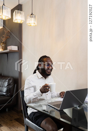 African American business man working from home, working on laptop and drinking coffee and relax while working from home African American business man working from home, working on laptop and drinking coffee and relax while working from home 127192027