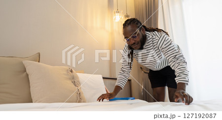 African American man doing housework at home on weekend, cleaning bed and cleaning bedroom African American man doing housework at home on weekend, cleaning bed and cleaning bedroom 127192087