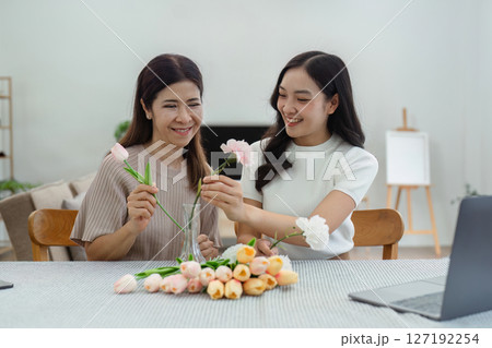 Mother and daughter arrange flower together at home on the weekend, family activities, mother and daughter do activities together on Mother's Day Mother and daughter arrange flower together at home on the weekend, family activities, mother and daughter do activities together on Mother's Day 127192254