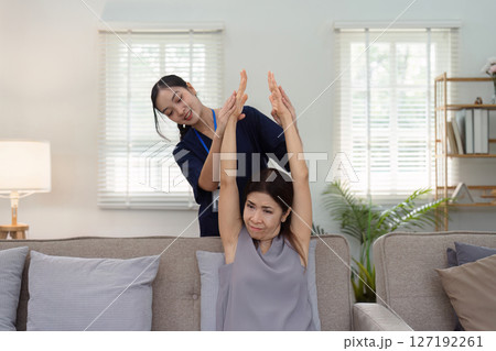 elderly Asian woman physical therapy with support of nurse or caregiver. Elderly woman doing exercises for patient with caregiver in home nursing 127192261