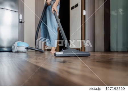 housekeeping beautiful young woman using a vacuum cleaner dust on floor. housework cleaning the floor under an electric vacuum cleaner 127192290