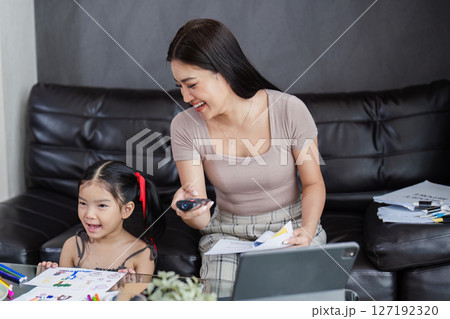 Businessman working at home. working woman talk on mobile and working on tablet and take care of her daughter during summer 127192320