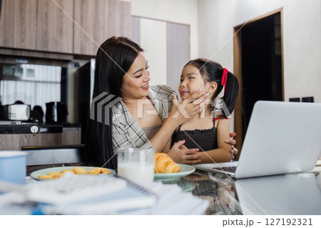Business woman working at home. Businessman working on laptop and feeding child 127192321