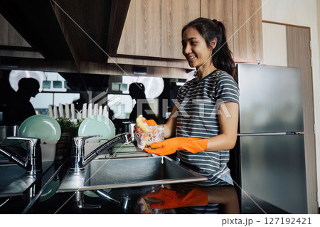 housewife cleans the house and washes the dishes at the sink. Cleaning home concept housewife cleans the house and washes the dishes at the sink. Cleaning home concept 127192421