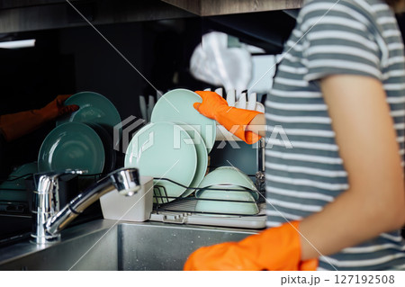 housewife cleans the house and washes the dishes at the sink. Cleaning home concept housewife cleans the house and washes the dishes at the sink. Cleaning home concept 127192508