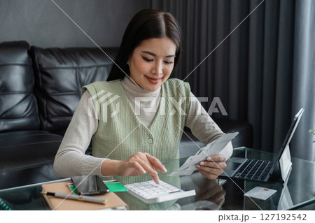 young woman calculating monthly home expenses, tax, bank account balance and credit card bills payment 127192542