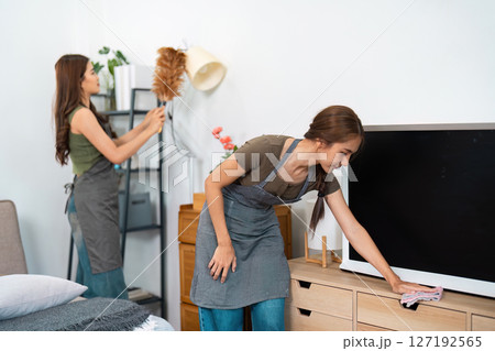 Cleaning teamwork: Two women collaborating to tidy the room Cleaning teamwork: Two women collaborating to tidy the room 127192565