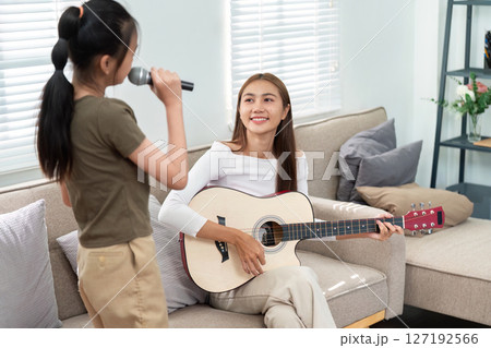 Mother and Daughter Music Session. Singing and playing guitar together in a joyful atmosphere. Mother and Daughter Music Session. Singing and playing guitar together in a joyful atmosphere. 127192566