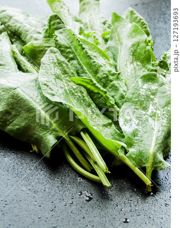 Pile of fresh green spinach sorrel leaves on the wooden table background, top view bunch of greens on the table with water drops. 127193693