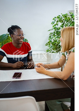 Two friends enjoying a warm conversation over coffee at home 127194577