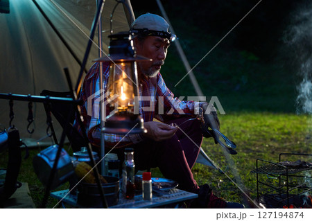 ステーキを食べるソロキャンパー　ソロキャンプ　シニア 127194874
