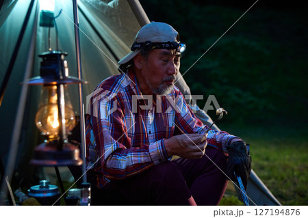 ステーキを食べるソロキャンパー　ソロキャンプ　シニア 127194876