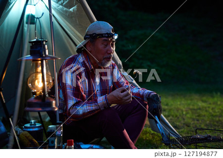 ステーキを食べるソロキャンパー　ソロキャンプ　シニア 127194877