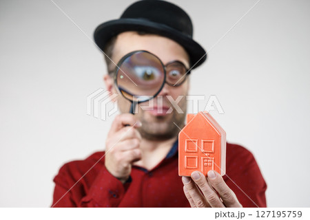 Man magnifying red house Man magnifying red house 127195759