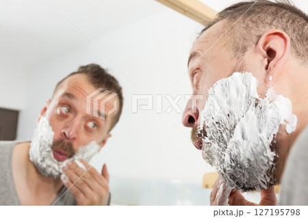 Man applying shaving cream on beard 127195798
