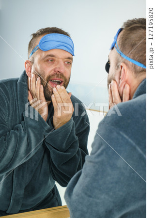 Sleepy man looking at mirror and yawning Sleepy man looking at mirror and yawning 127195820