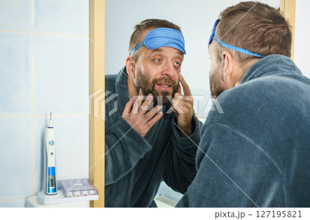 Sleepy man looking at mirror Sleepy man looking at mirror 127195821