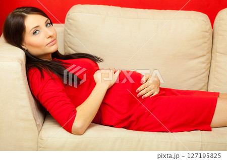 pregnant woman relaxing on sofa touching her belly pregnant woman relaxing on sofa touching her belly 127195825