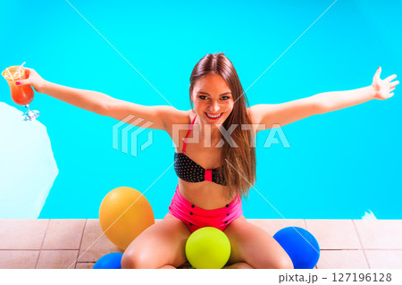 Happy woman with balloons and cocktail at poolside Happy woman with balloons and cocktail at poolside 127196128