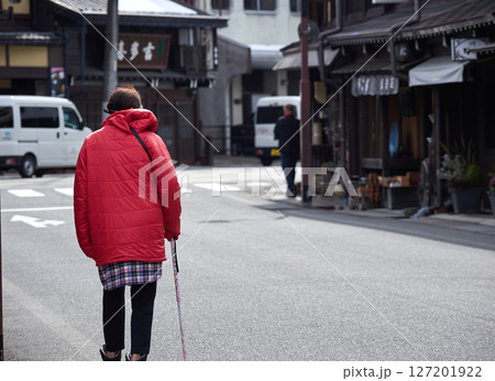 冬の高山市の古い町並みで歩く一人のシニア女性の姿 127201922
