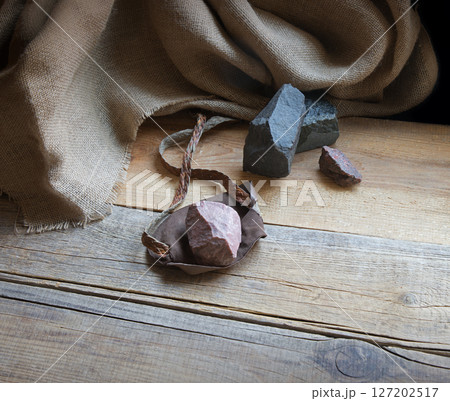 An antique leather sling lies on wooden desk 127202517