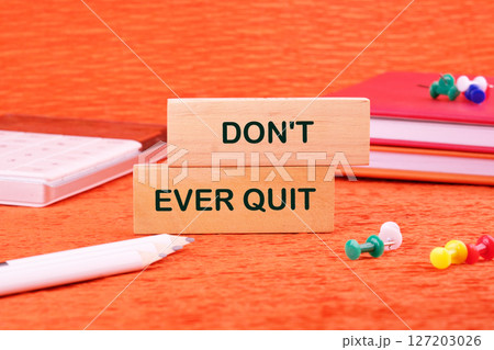 Workforce Reduction, Downsizing, Reorganization, Restructuring concept. Text DO NOT EVER QUIT made of wooden blocks on an orange background with stationery lying next to it Workforce Reduction, Downsizing, Reorganization, Restructuring concept. Text DO NOT EVER QUIT made of wooden blocks on an orange background with stationery lying next to it 127203026