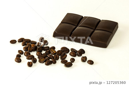 Tiles of dark chocolate and coffee beans on a light background Tiles of dark chocolate and coffee beans on a light background 127205360