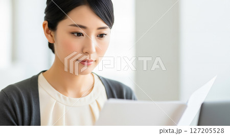 仕事の資料に目を通す女性 仕事の資料に目を通す女性 127205528