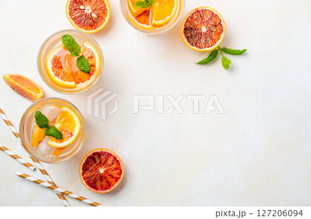 Cold refreshing drink with blood orange slices in a glass on a white concrete background. Top view, flat lay, copy space. Cold refreshing drink with blood orange slices in a glass on a white concrete background. Top view, flat lay, copy space. 127206094