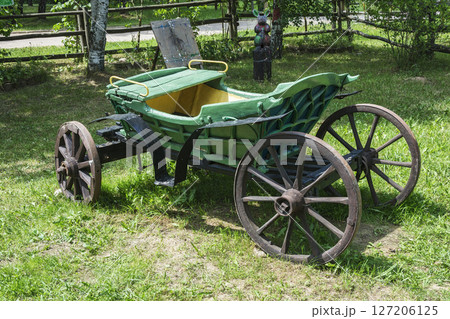 An old carriage for trips in a harness with a horse stands on the green grass An old carriage for trips in a harness with a horse stands on the green grass 127206125