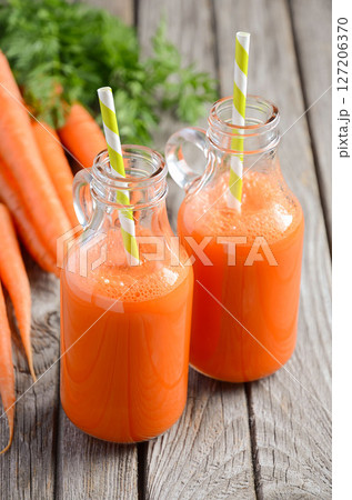 Fresh carrot juice in a bottles on rustic wooden background, selective focus Fresh carrot juice in a bottles on rustic wooden background, selective focus 127206370