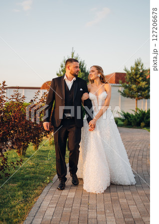 Gentle and happy bride and groom at sunset walking in the park. Romantic. Gentle and happy bride and groom at sunset walking in the park. Romantic. 127206678