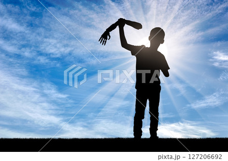 Silhouette of a disabled child holding a prosthetic arm against a bright, sunlit sky Silhouette of a disabled child holding a prosthetic arm against a bright, sunlit sky 127206692